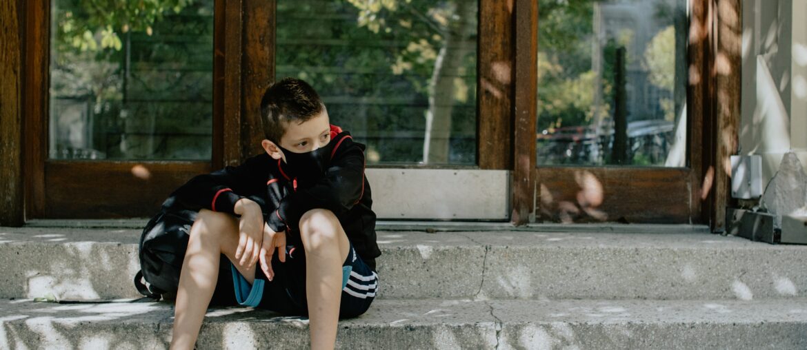 Boy with mask on the steps waiting for school