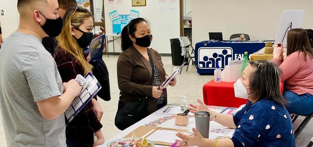 Hmong PTA President Caitlin Lee speaks with an Eau Claire family about Hmong resources.