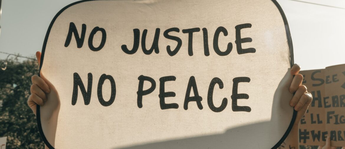 Protestor holding up a sign that says "No Justice No Peace"