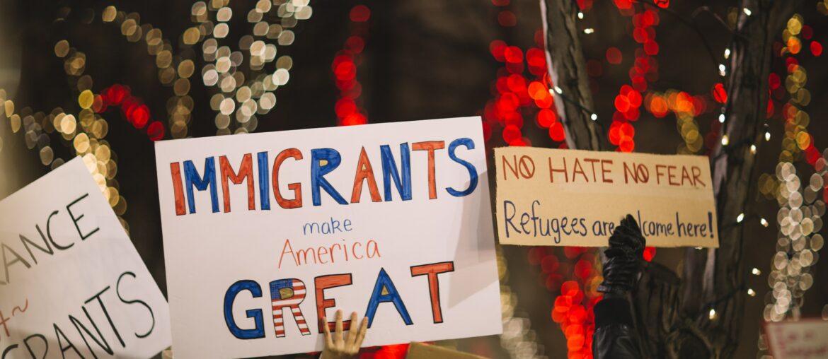 Sign says "Immigrants Make America Great" at a rally