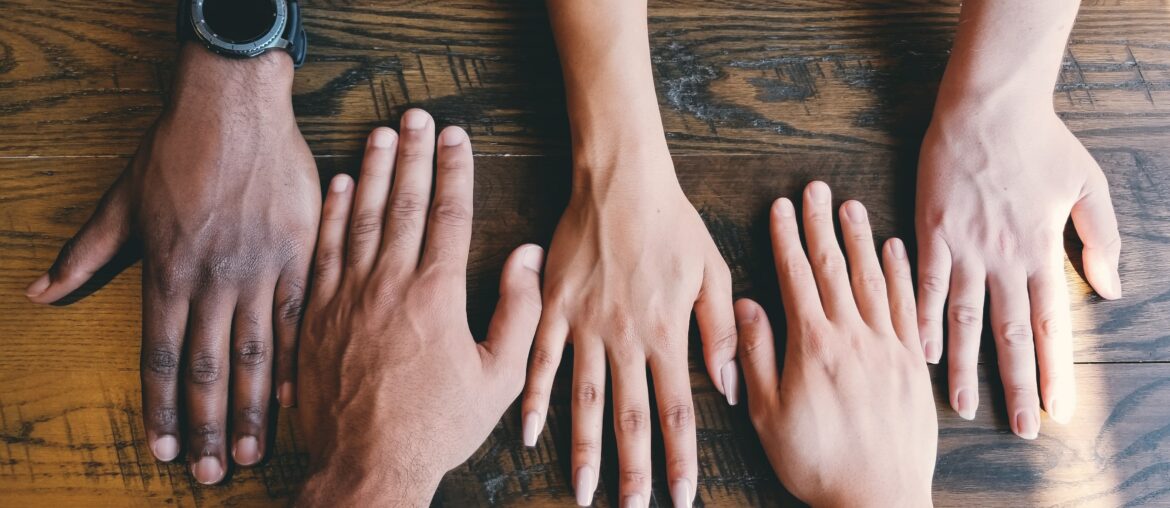 row of hands with their palms on the table