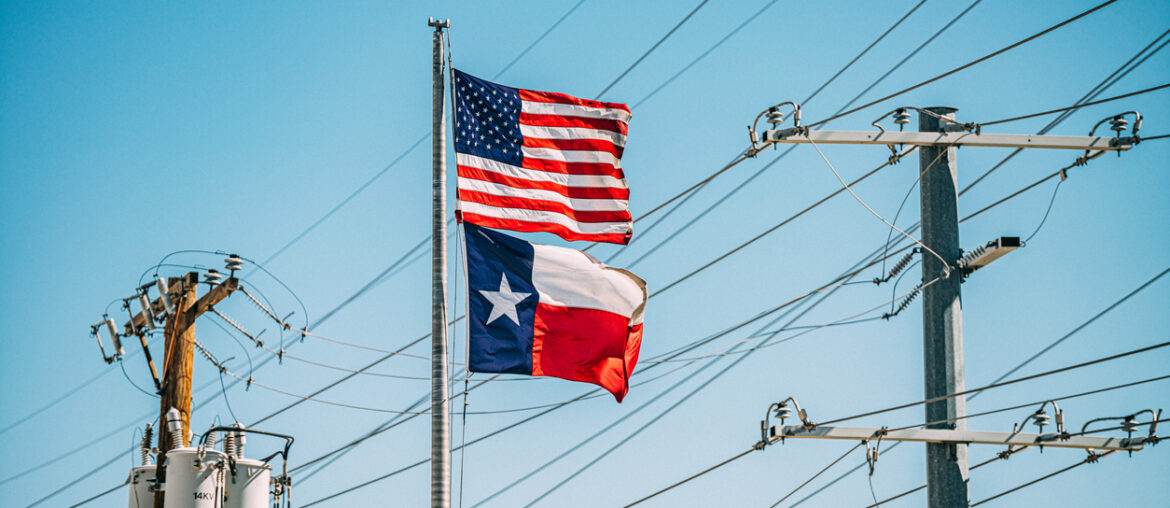 American USA Flag and Texas State Flag flying together in front of power lines. The state of Texas operates its electrical grid through a deregulated market, overseen by the Electric Reliability Council of Texas (ERCOT), who coordinates the flow of electricity and ensures grid reliability.